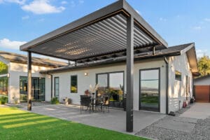White aluminum louvered pergola with built-in lighting system covering outdoor patio dining area.