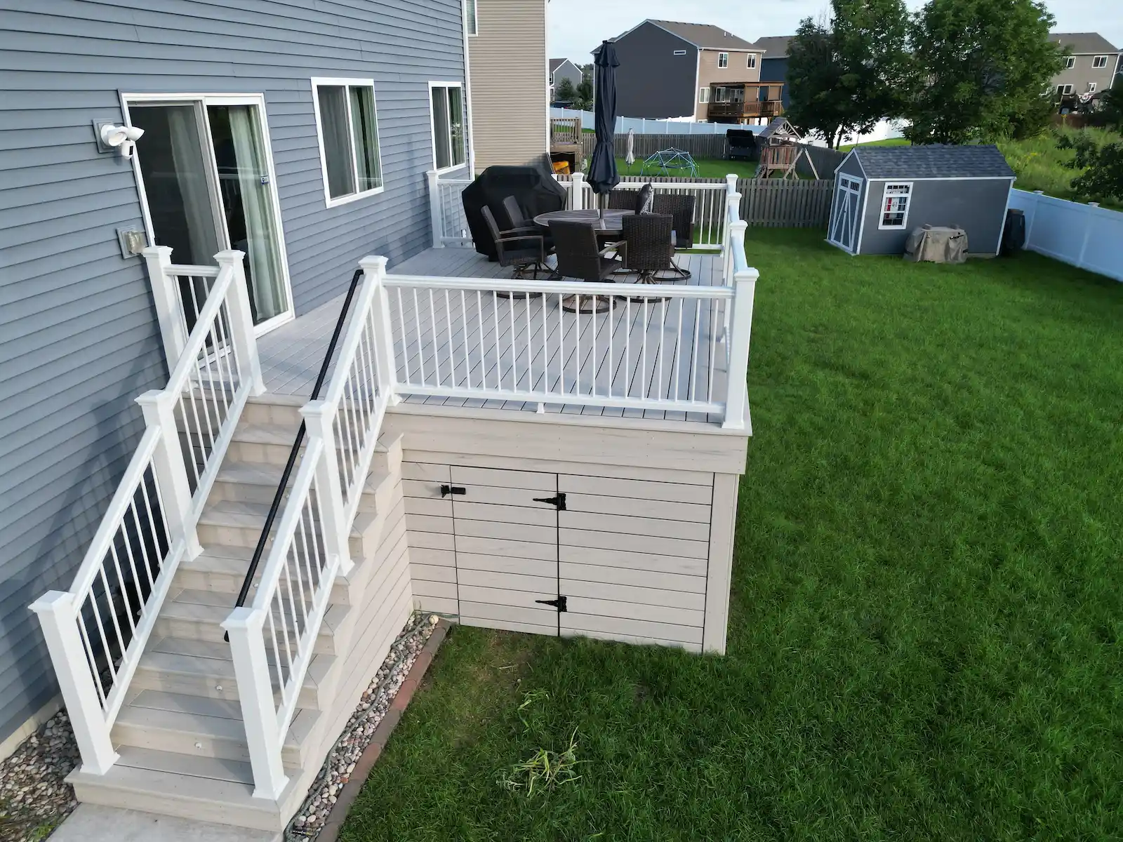 horizontal-composite-deck-skirting Raised composite deck with horizontal skirting and an access door.