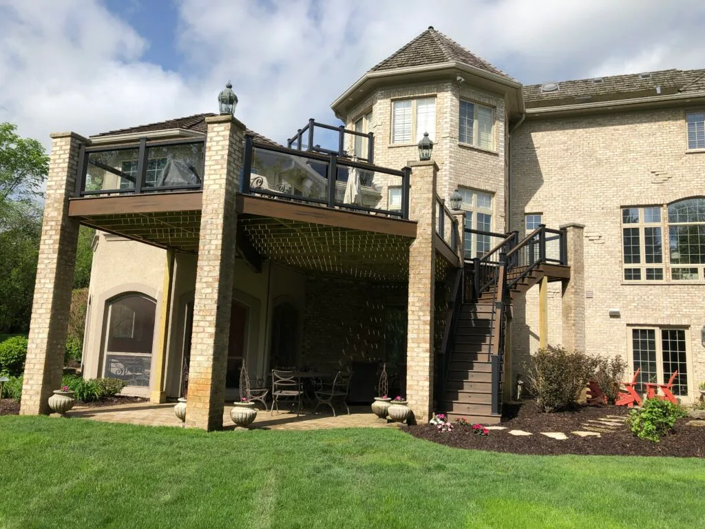 Newly built Trex deck with glass infill railings supported on brick pillars in Chicago suburbs IL.