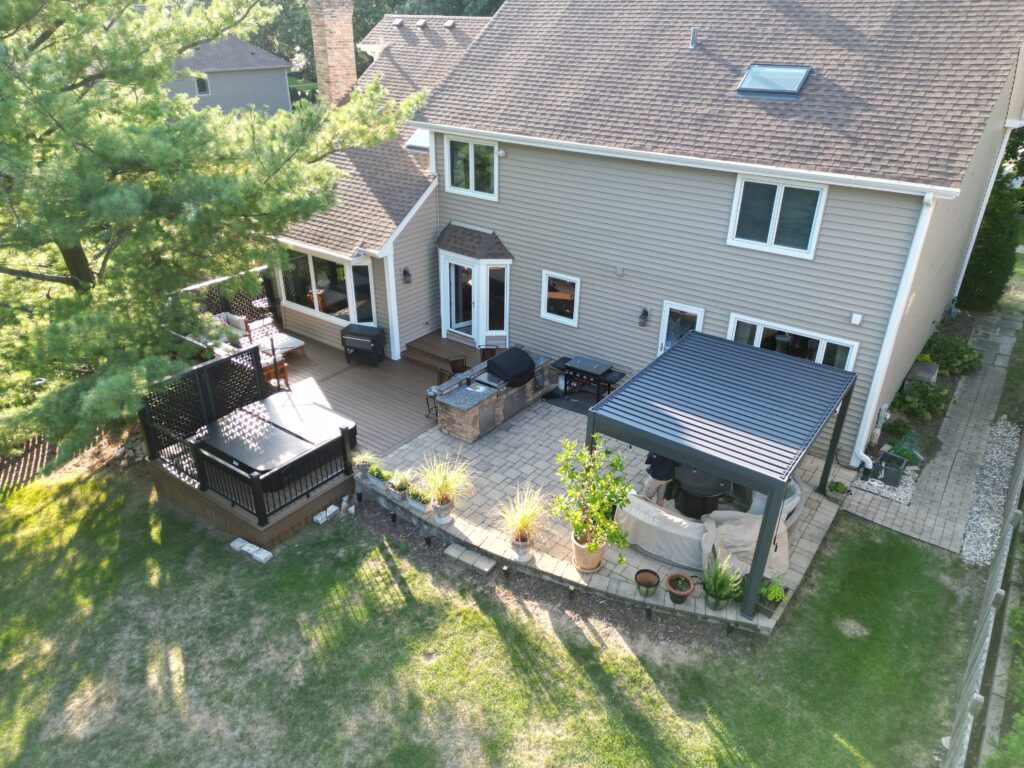 Louvered roof covering a patio with an adjacent hot tub, seamlessly integrated into composite decking with hybrid railings and privacy screens.
