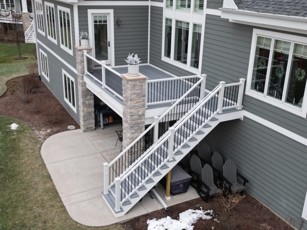 Elevated Trex composite deck with Trex RainEscape drainage system and a leading staircase designed to blend seamlessly with the Plainfield homeowner’s home and backyard.
