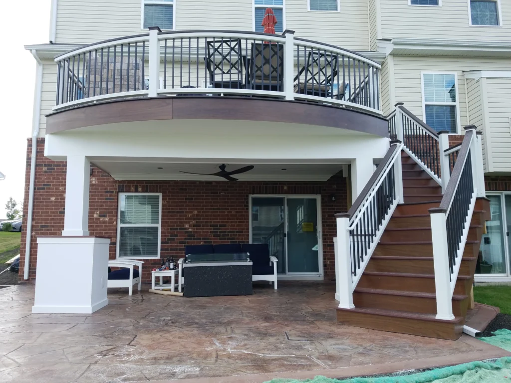 Trex Transcend® composite deck in Lava Rock with white accents featuring a curved deck design and a leading staircase supported by white posts in Chicago IL