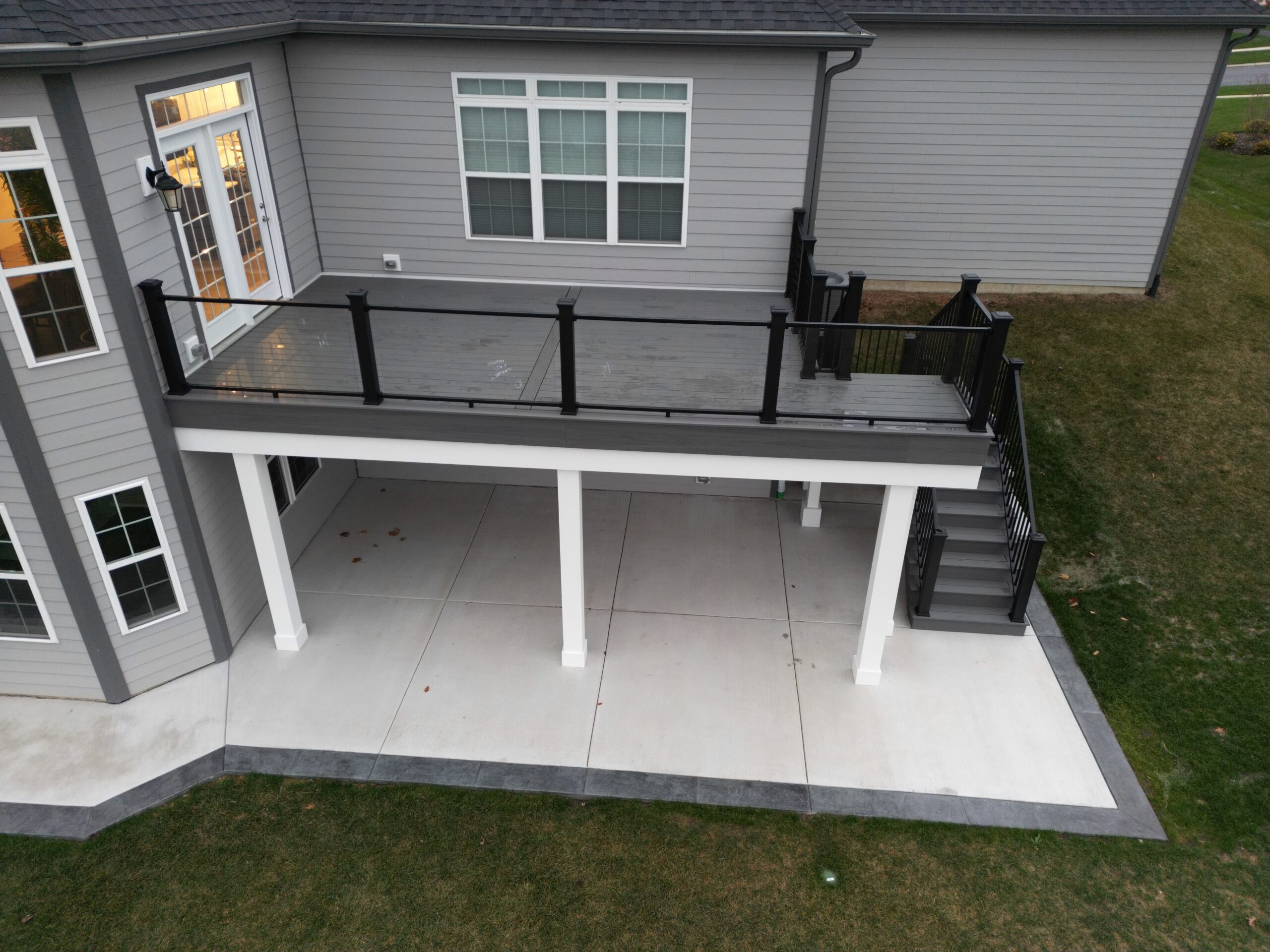 Raised composite deck with glass infill railings and a leading staircase.