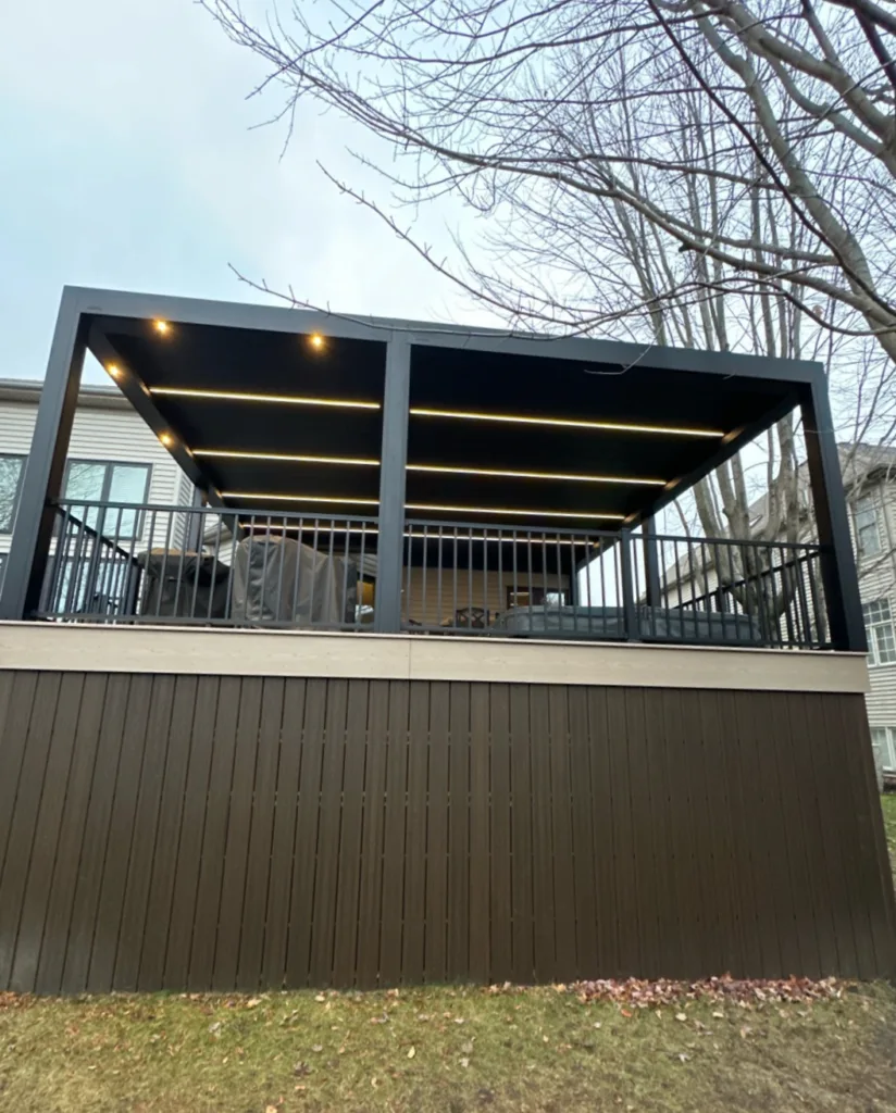 Trex composite deck with two-tone decking, custom skirting, integrated hot tub, and motorized louvered roof pergola in a luxury backyard outdoor living space.