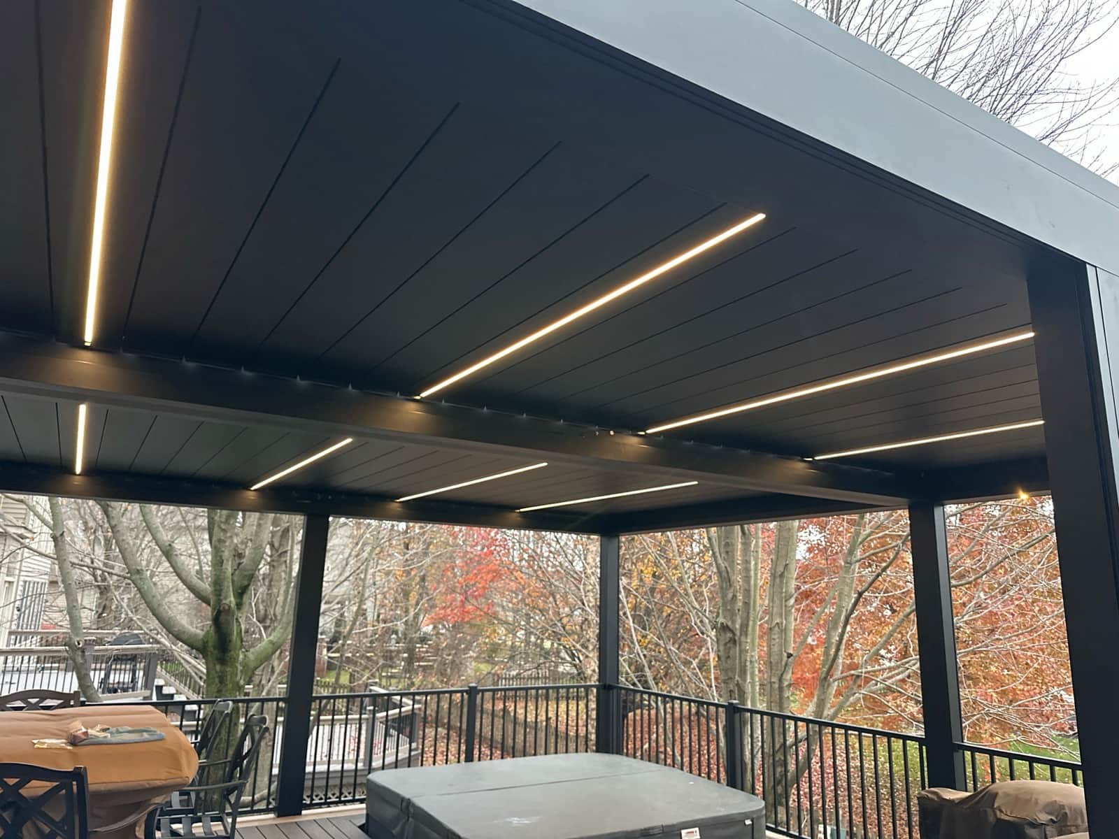 Motorized louvered roof pergola integrated with LED lighting sitting on top of a Trex deck.