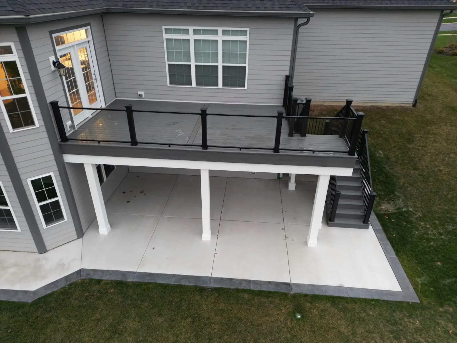 composite-deck-with-glass-infill-railings Raised composite deck with glass infill railings and a leading staircase.