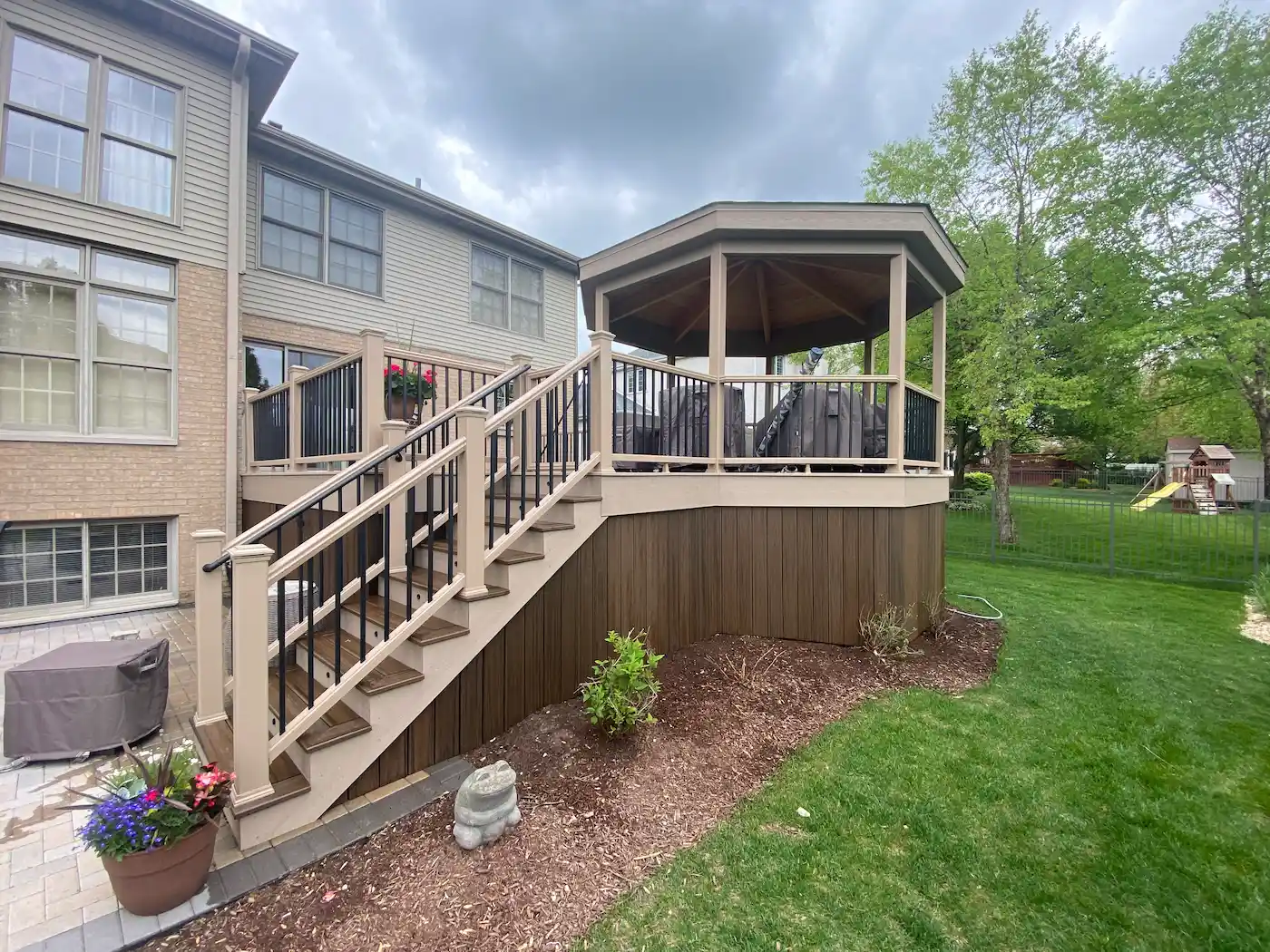 composite-trex-deck-freestanding-gazebo Two-tone Trex composite deck featuring contrasting fascia, vertical deck skirting, integrated LED stair lights, and a freestanding outdoor gazebo in the Chicago suburbs.